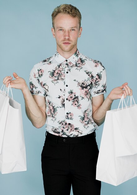 Jeune homme avec des sacs à provisions à la recherche de la caméra