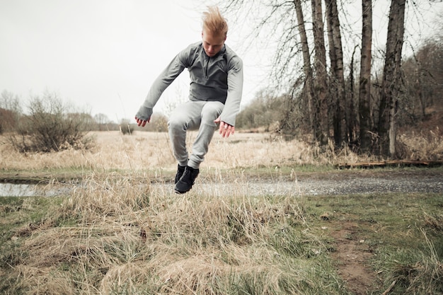 Jeune homme sautant par-dessus le foin