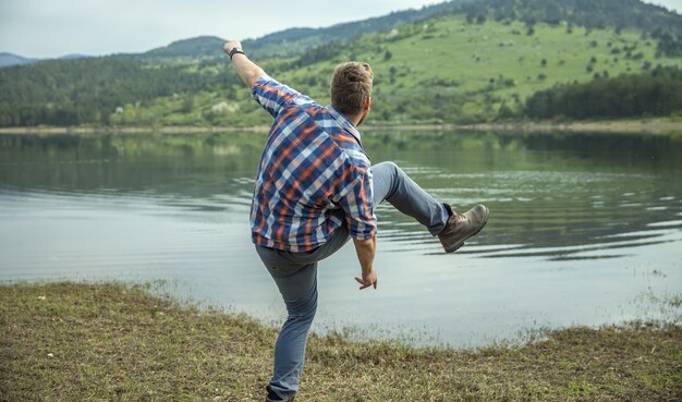 Jeune homme sautant une pierre sur l'eau du lac