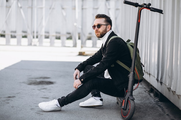 Jeune homme avec scooter, assis sur le sol