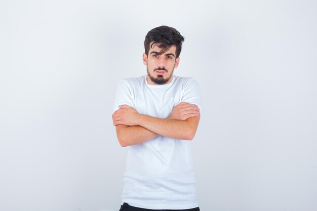 Jeune homme se serrant dans ses bras ou se sentant froid en t-shirt blanc et ayant l'air sensible