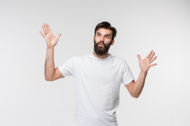 Le jeune homme séduisant à la surprise isolé sur blanc