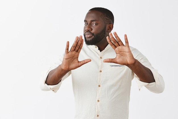 Photo gratuite jeune homme sérieux posant contre le mur blanc