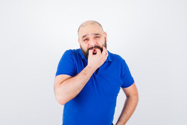 Jeune homme sifflant en posant en t-shirt et ayant l'air mignon. vue de face.