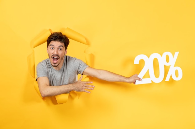 Jeune homme avec signe d'inscription sur le mur de papier jaune déchiré