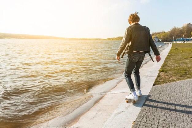 Jeune homme avec un skateboard près de la mer