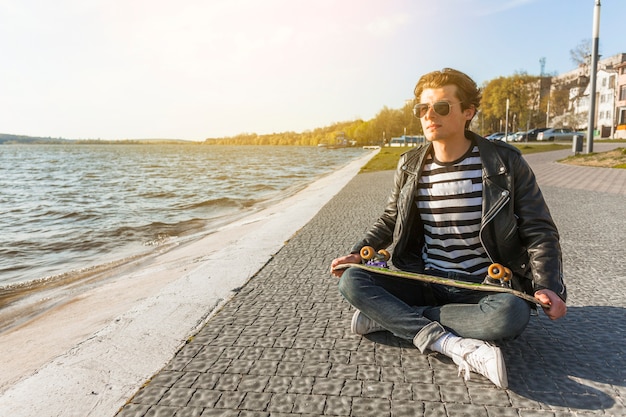 Jeune homme avec un skateboard près de la mer