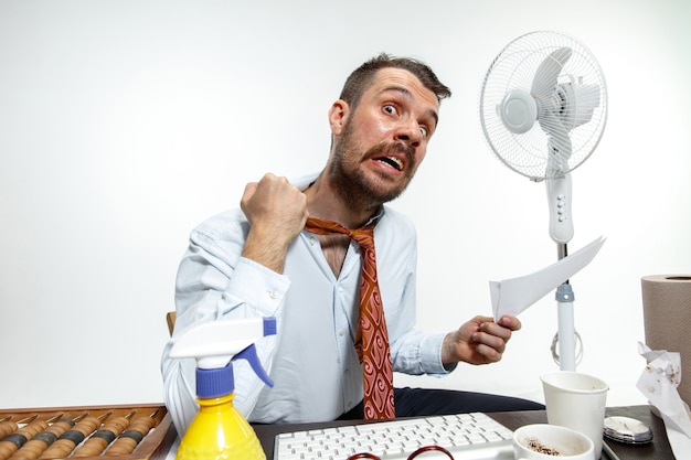 Jeune homme souffrant de la chaleur au bureau