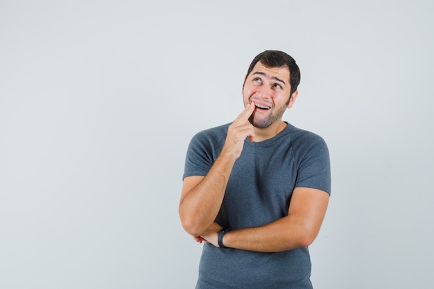 Jeune homme souffrant de maux de dents en t-shirt gris et à mal à l'aise