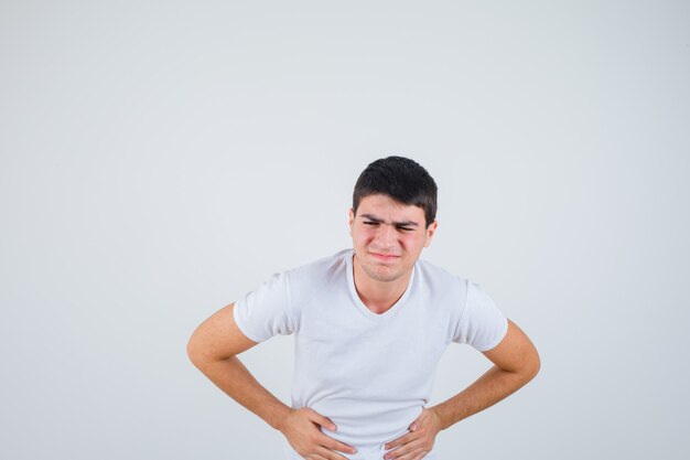 Jeune homme souffrant de maux d'estomac en t-shirt et à la douleur. vue de face.