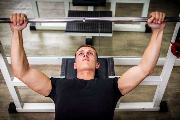 Jeune homme, soulever des poids dans une salle de sport