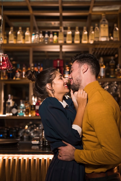 Jeune homme souriant, étreindre, à, femme heureuse, près, bar, comptoir