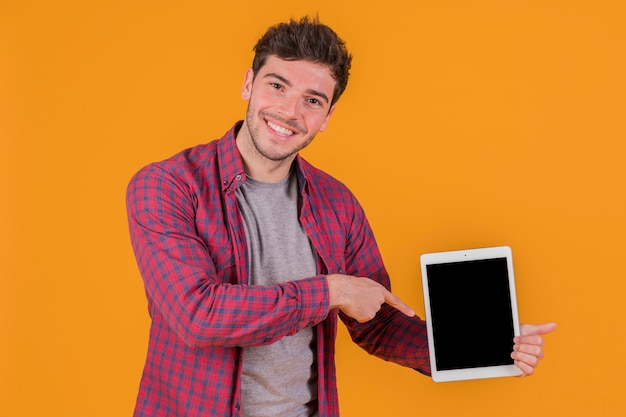Un jeune homme souriant, pointant son doigt vers une tablette numérique sur un fond orange