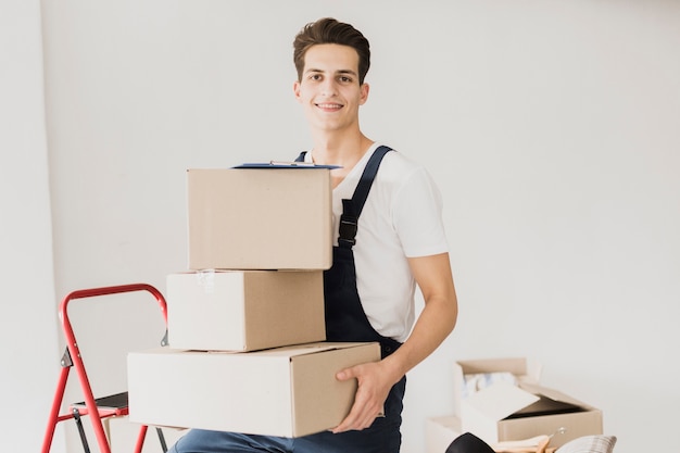 Jeune homme souriant tenant des boîtes en carton