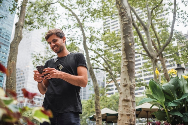 Jeune homme souriant tout en regardant l'écran du téléphone