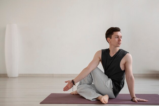 Jeune homme spirituel pratiquant le yoga à l'intérieur
