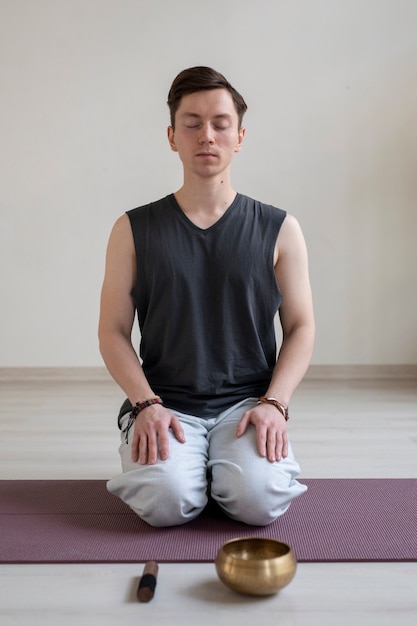 Photo gratuite jeune homme spirituel pratiquant le yoga à l'intérieur