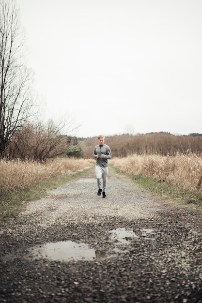 Jeune homme sportif, courir sur un chemin de terre dans le champ