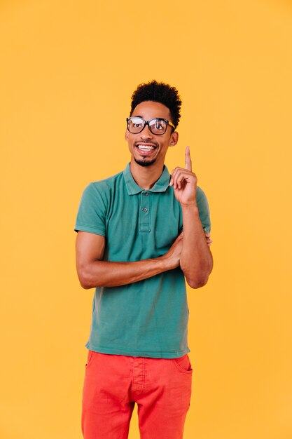 Jeune homme sportif à lunettes posant. Superbe modèle masculin en t-shirt vert souriant.