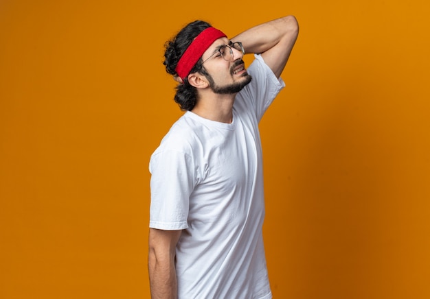 Un jeune homme sportif mécontent portant un bandeau avec un bracelet saisit le cou douloureux