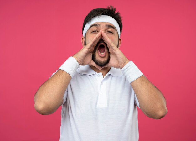 Jeune homme sportif portant un bandeau et un bracelet appelant quelqu'un