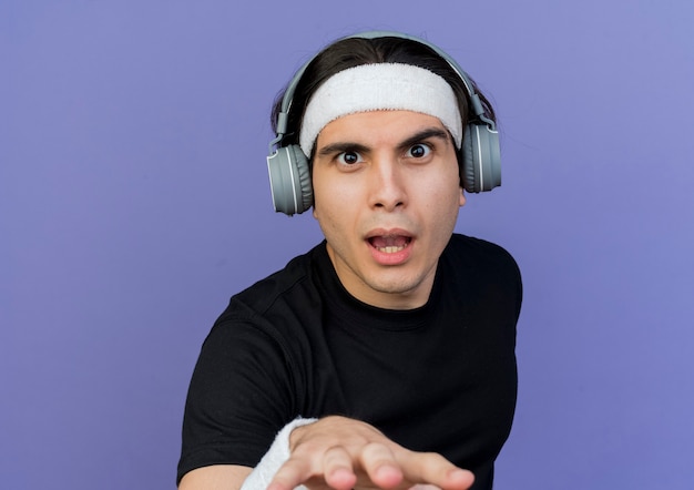 Photo gratuite jeune homme sportif portant des vêtements de sport et un bandeau avec un casque surpris