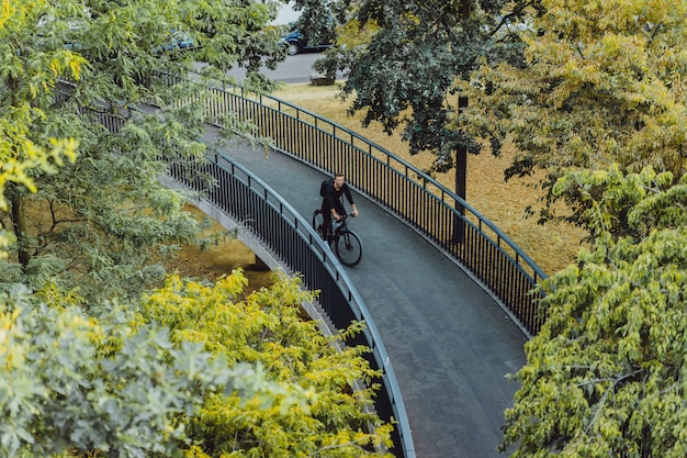 Photo gratuite jeune homme sportif à vélo dans une ville européenne. sports en milieu urbain.