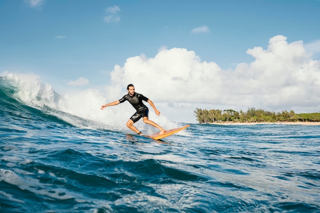 Jeune homme surfe sur l'océan vagues d'eau claire