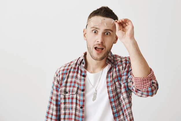 Jeune homme surpris et étonné avec des lunettes posant