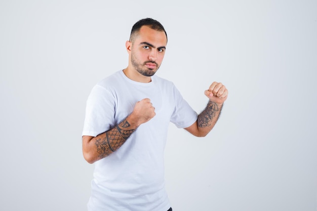 Jeune homme en t-shirt blanc debout dans une pose de boxeur et à la grave