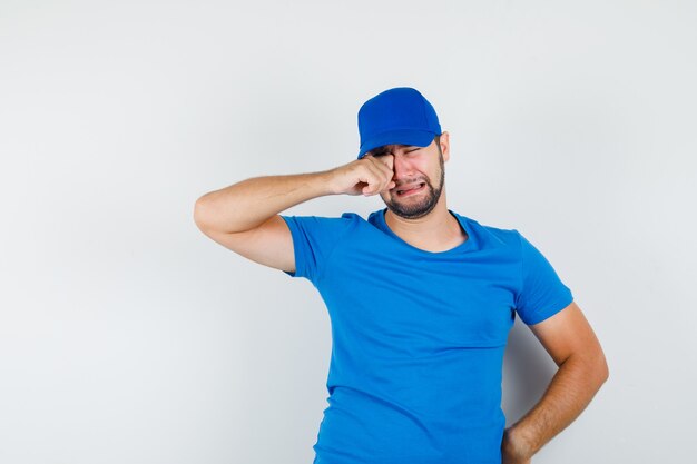 Jeune homme en t-shirt bleu et casquette pleurant comme un enfant et à la dépression