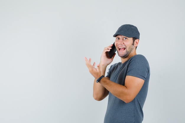 Jeune homme en t-shirt cap parler sur téléphone mobile et à heureux