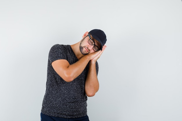 Jeune homme en t-shirt et casquette, jeans s'appuyant sur les paumes comme oreiller et à la calme