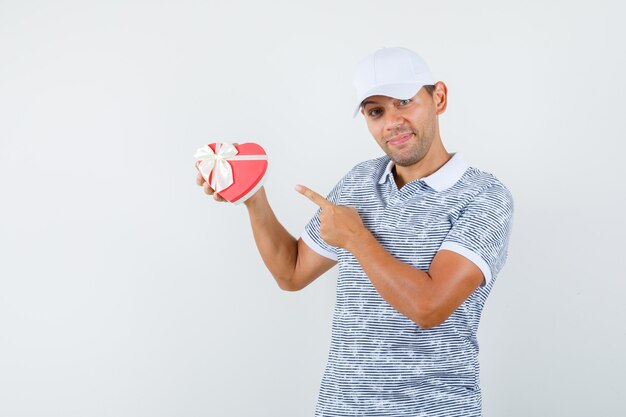 Jeune homme en t-shirt et casquette pointant sur la boîte actuelle et à la bonne humeur