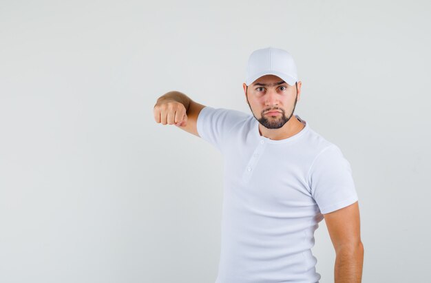 Jeune homme en t-shirt, casquette pointant vers la caméra et regardant en colère, vue de face.