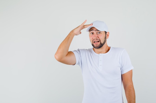 Jeune homme en t-shirt, casquette touchant sa casquette et regardant excité, vue de face.