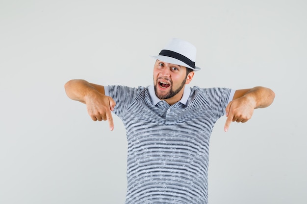 Jeune homme en t-shirt, chapeau pointant vers le bas et regardant concentré, vue de face.