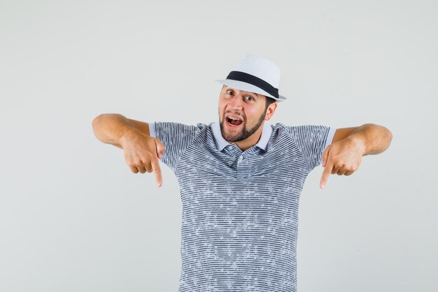 Jeune homme en t-shirt, chapeau pointant vers le bas et regardant concentré, vue de face.