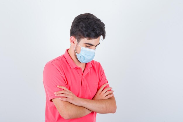 Jeune homme en t-shirt debout avec les bras croisés et l'air confiant, vue de face.