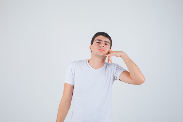 Jeune homme en t-shirt montrant le geste du téléphone et à la confiance en soi, vue de face.