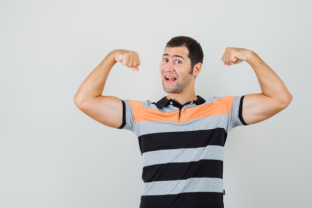 Jeune homme en t-shirt montrant ses muscles des bras et à la flexibilité