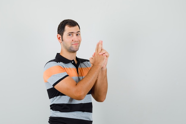 Jeune homme en t-shirt montrant le signe du pistolet et à la confiance