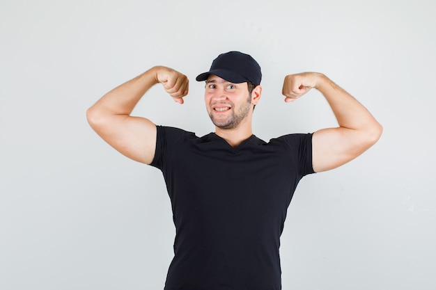 Jeune homme en t-shirt noir, casquette montrant des muscles et à la gaieté