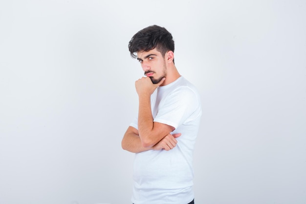 Jeune homme en t-shirt posant debout et l'air confiant