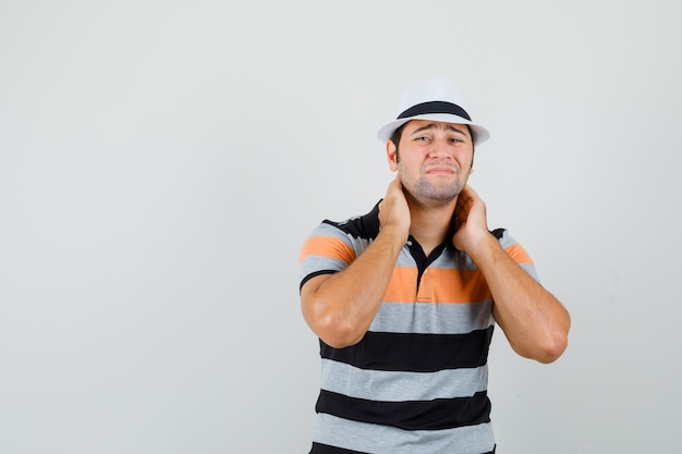 Jeune homme en t-shirt rayé, chapeau souffrant de maux de cou et à l'espace douloureux pour le texte