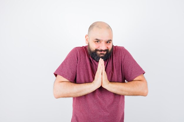 Jeune homme en t-shirt rose montrant le geste de namaste, vue de face.