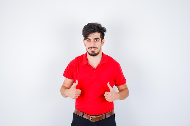 Jeune homme en t-shirt rouge montrant les pouces vers le haut et à la grave