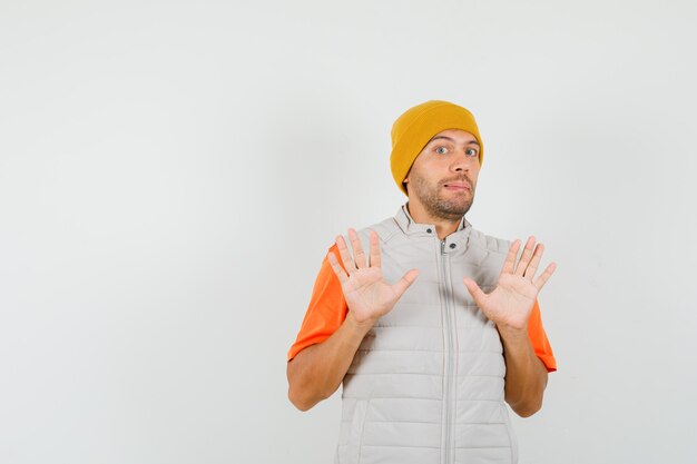 Jeune homme en t-shirt, veste, chapeau ne montrant aucun geste et à la peur, vue de face.