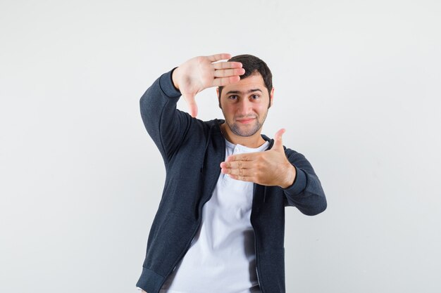 Jeune homme en t-shirt, veste faisant le geste du cadre et à la vue de face, heureux.