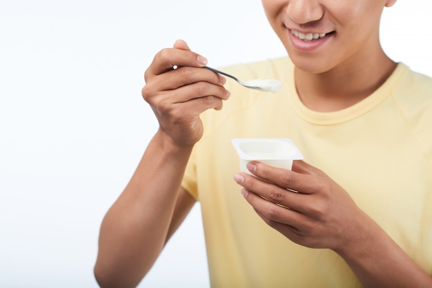Jeune homme avec une tasse de yaourt en plastique